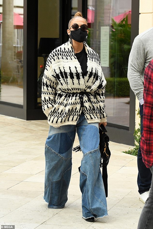 Superstar style: Lopez, 51, looked casual and chic in a pair of patchwork wide leg jeans and a chunky cardigan